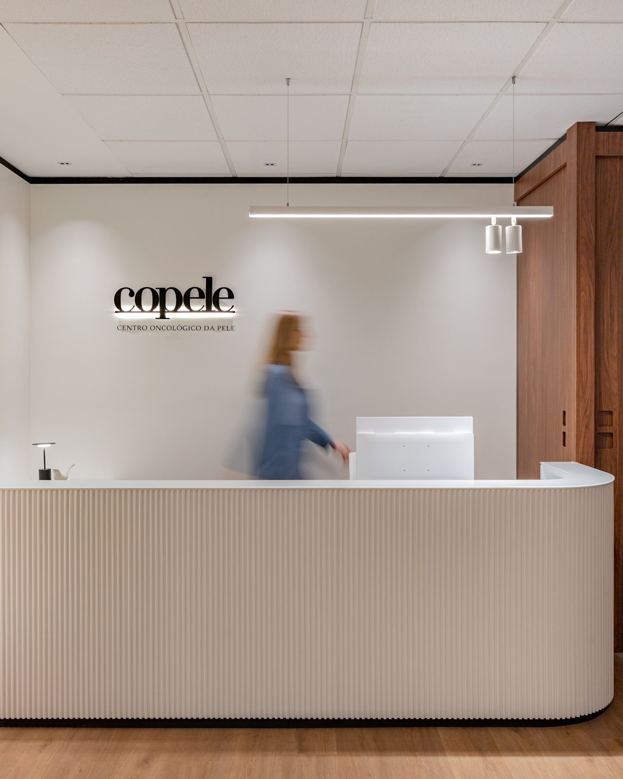 Balcão de recepção e check-in da COPELE, com o letreiro da clínica ao fundo, em Lajeado/RS
